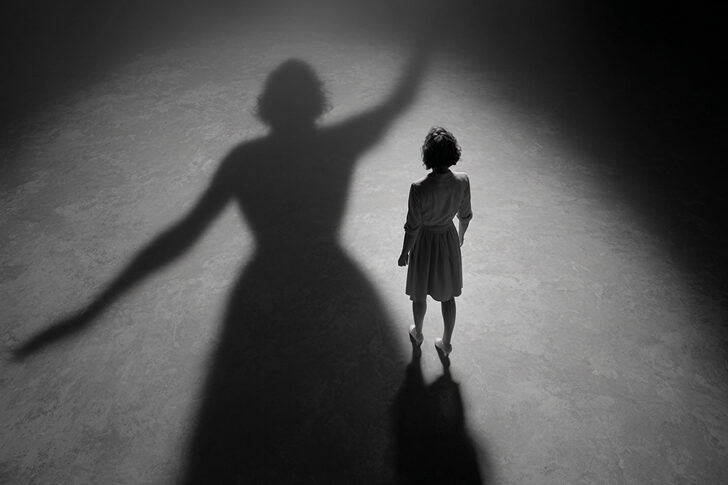 Woman standing on a stage looking at her shadow